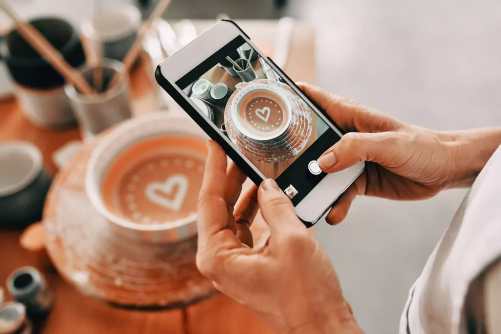 person taking a picture of their latte with their cellphone to post on social media