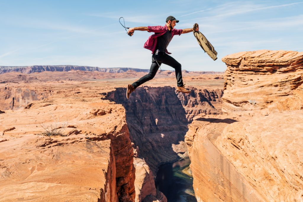 A man is jumping over a chasm.