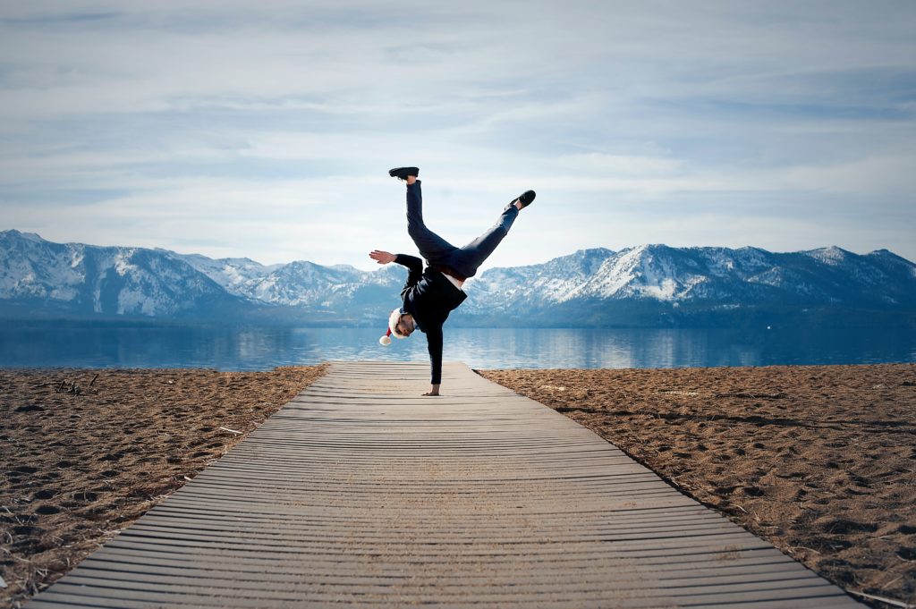 A man turns a cartwheel on a boardwalk.