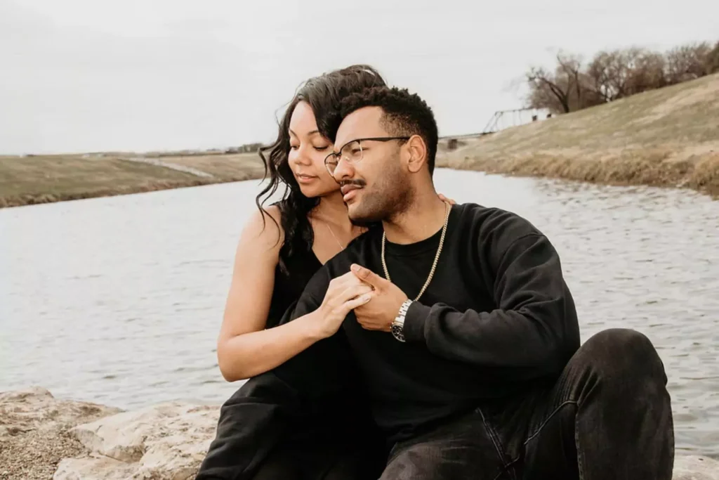 a woman and man sitting by a lake, cuddling. How to win a man's heart
