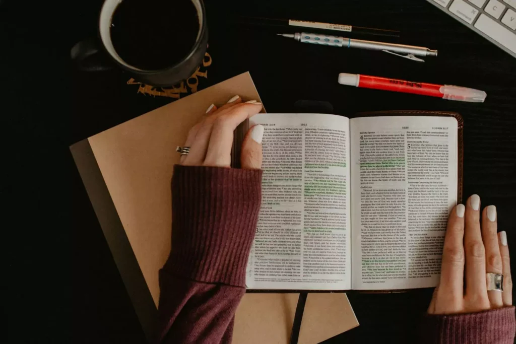 Woman's hands on an open Bible, praying Scripture