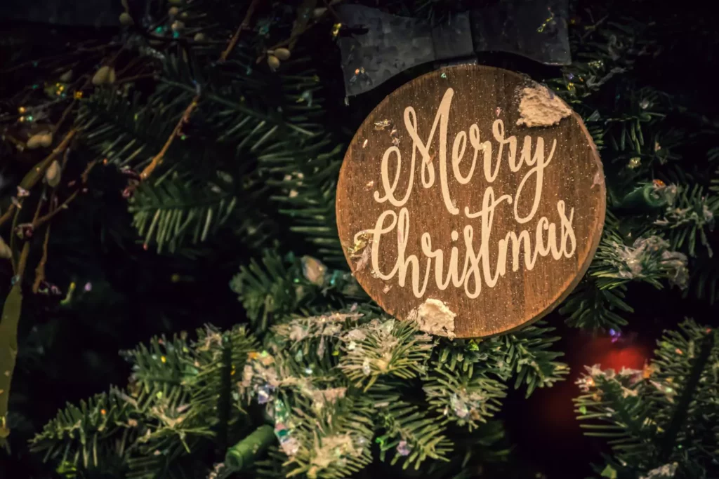 wood ornament on a Christmas tree that says Merry Christmas