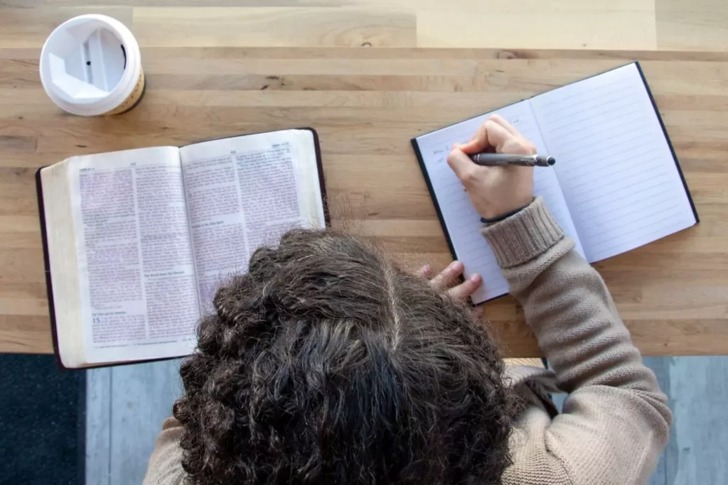 woman reading her Bible and writing in her journal