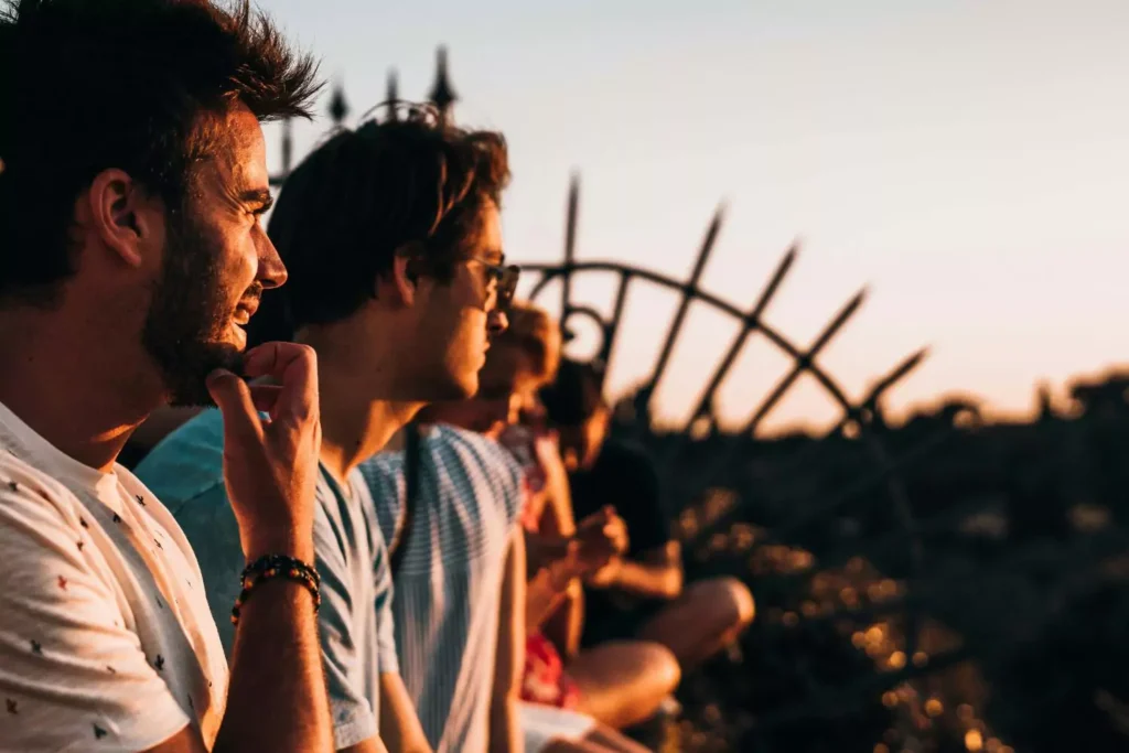 men sitting next to a fence, learning how to speak up