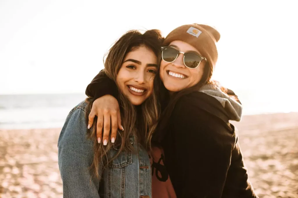 two women hugging on the beach - making peace with your roommate