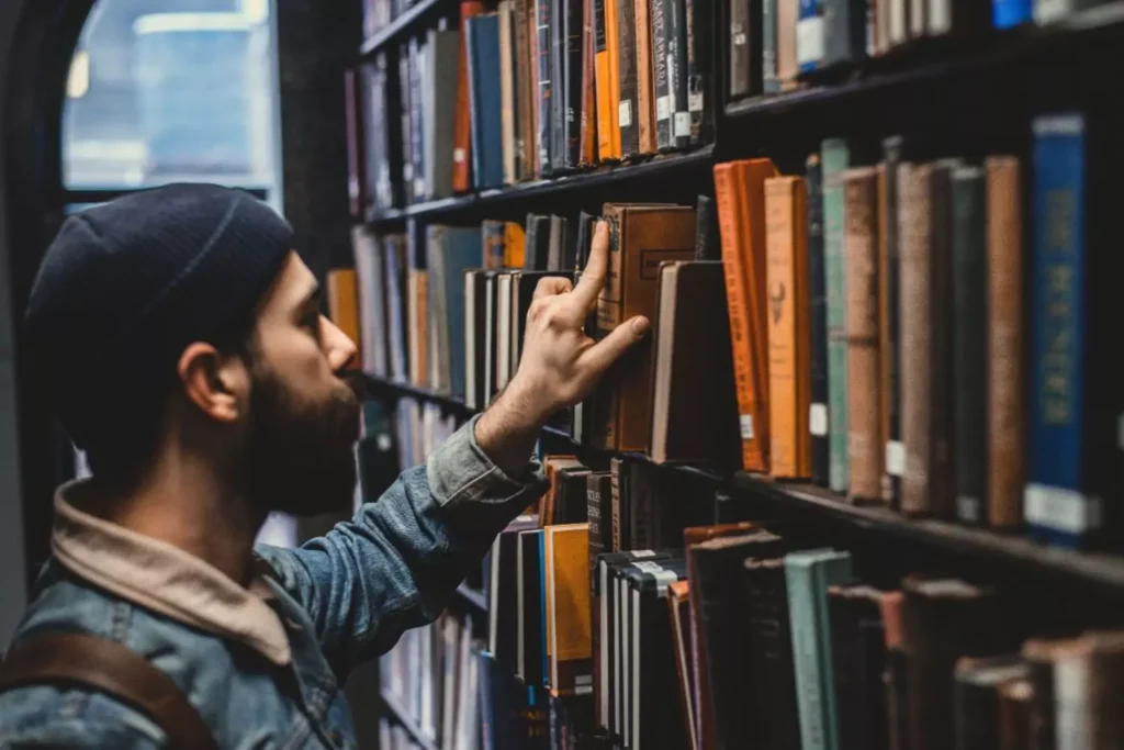 a man selecting a book from a library shelf, preparing to do good works