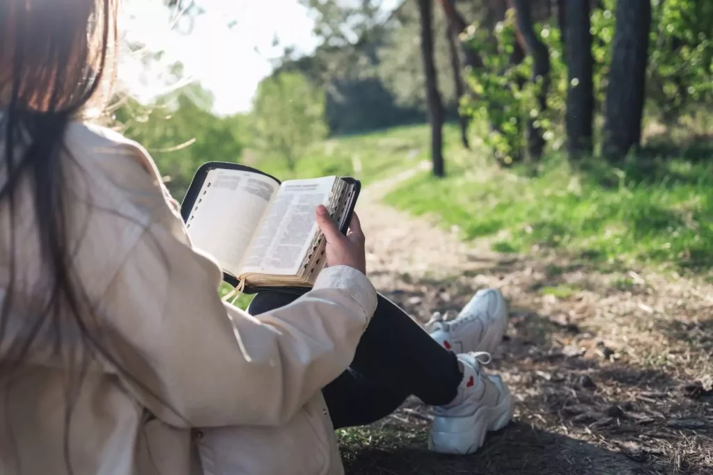 girl reading her bible amongst trees