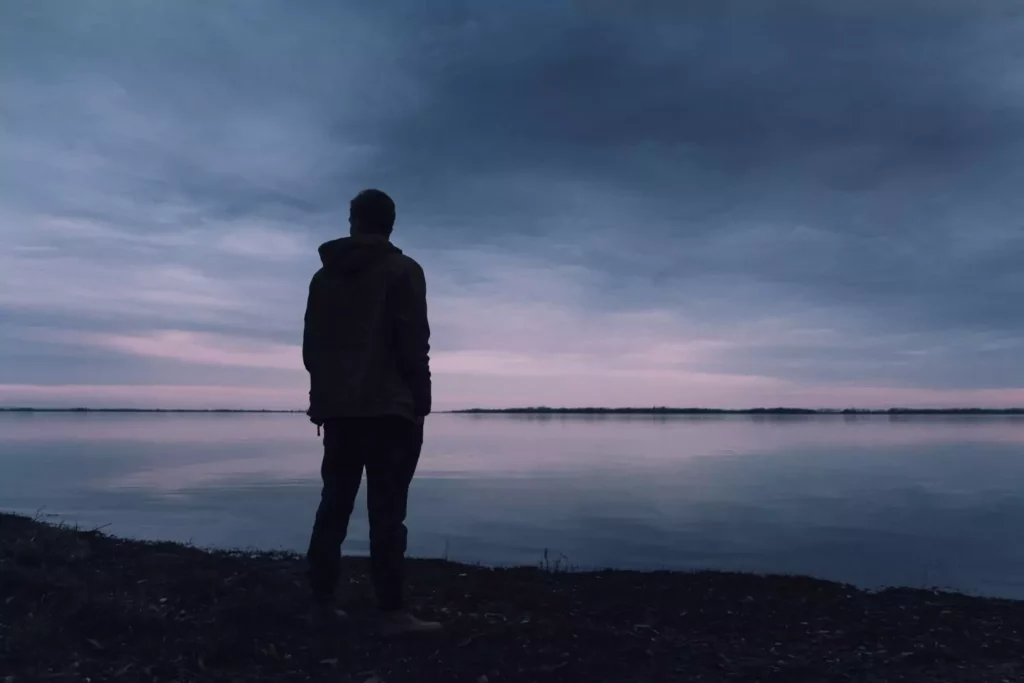 man looking out over a dark lake