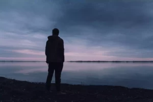 man looking out over a dark lake