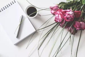 a notebook, coffee and pink flowers