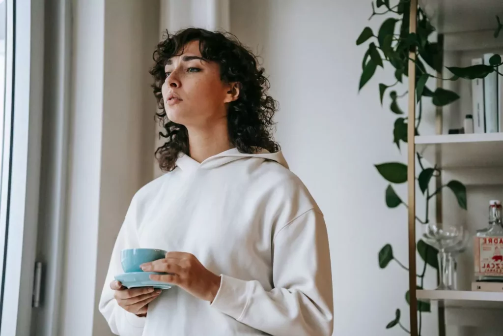 woman holding coffee looking out a window thinking about lies