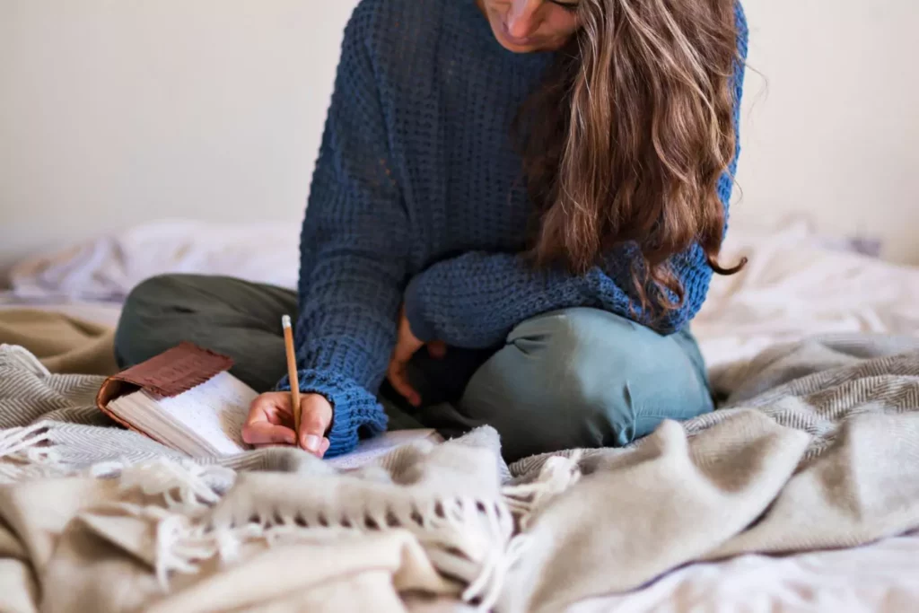 woman sitting on her bed writing her prayers