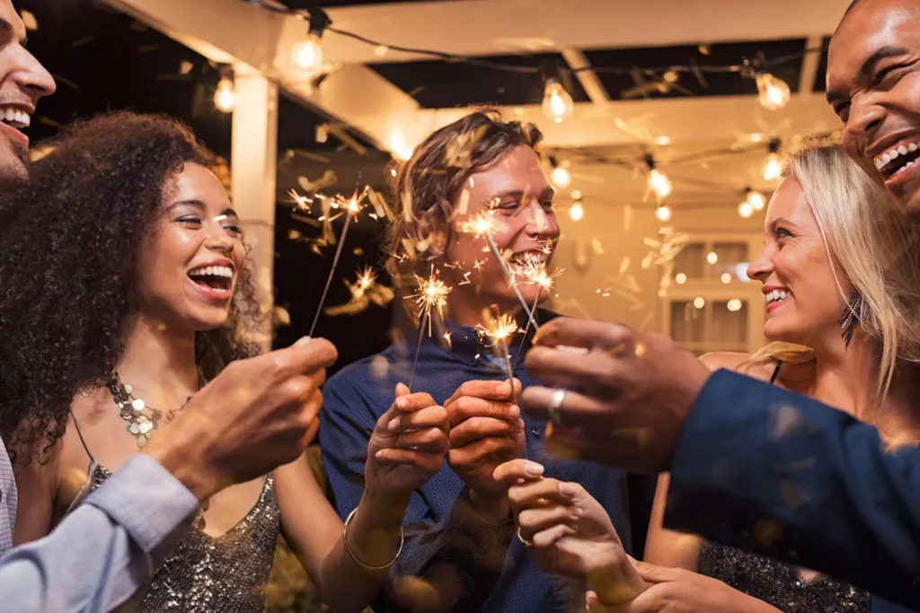 a group of friends at a New Year's party holding sparklers