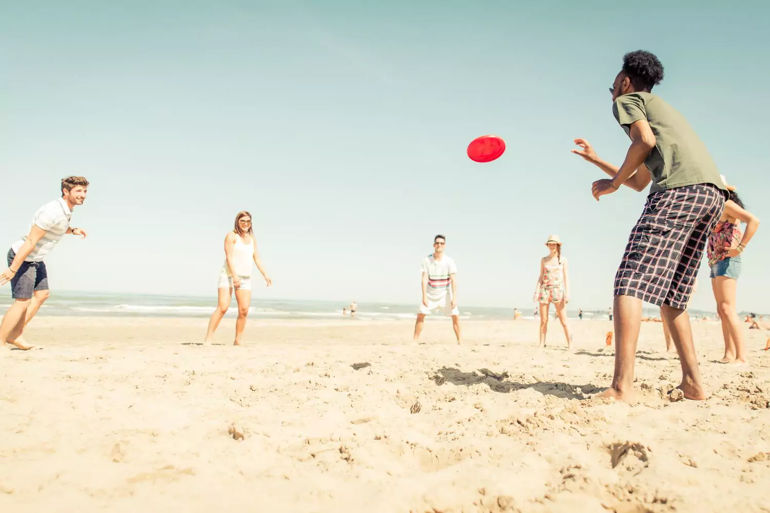 a group of friends playing frisbee on the beach