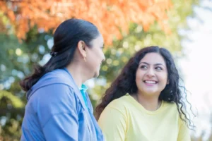 an older and a younger woman talking and smiling - the older is a spiritual mother to the younger