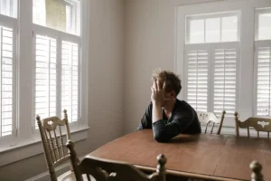 a man sitting at a table, hurt by his Christian friends