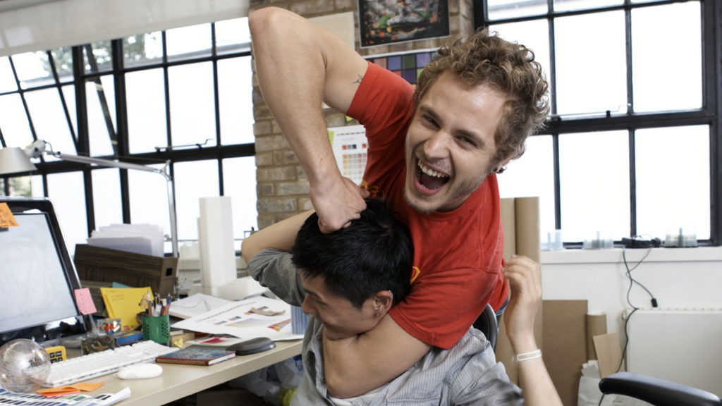 guys in office playfully head-locking another guy