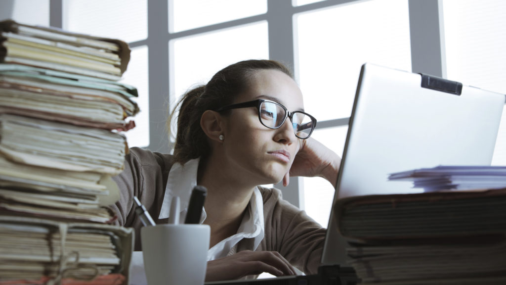 young woman staring at work computer looking bored