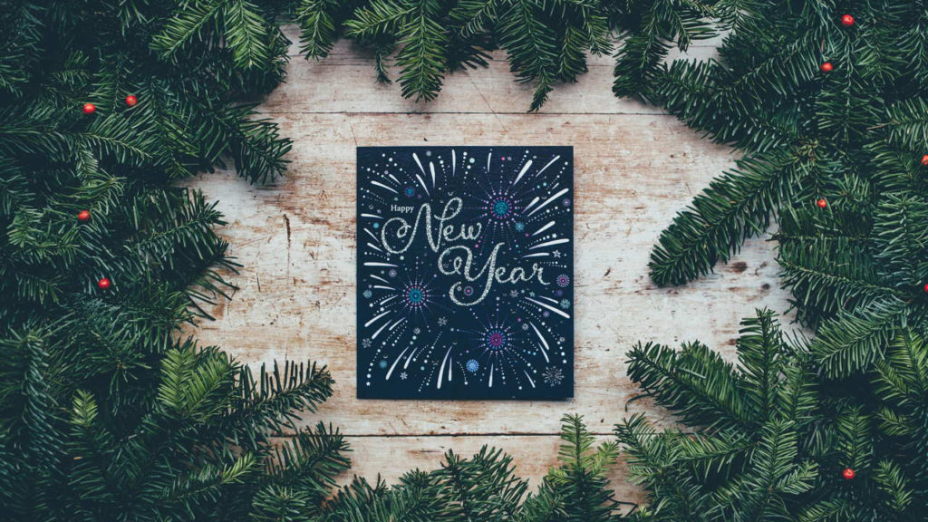 new year sign on table with evergreen branches around it