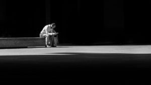 person sitting on bench alone in blackness
