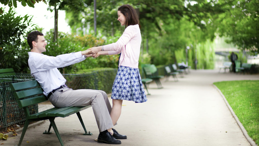 Woman playfully pulling man off bench