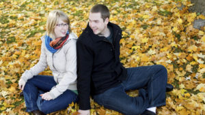 couple sitting on patch of fallen leaves