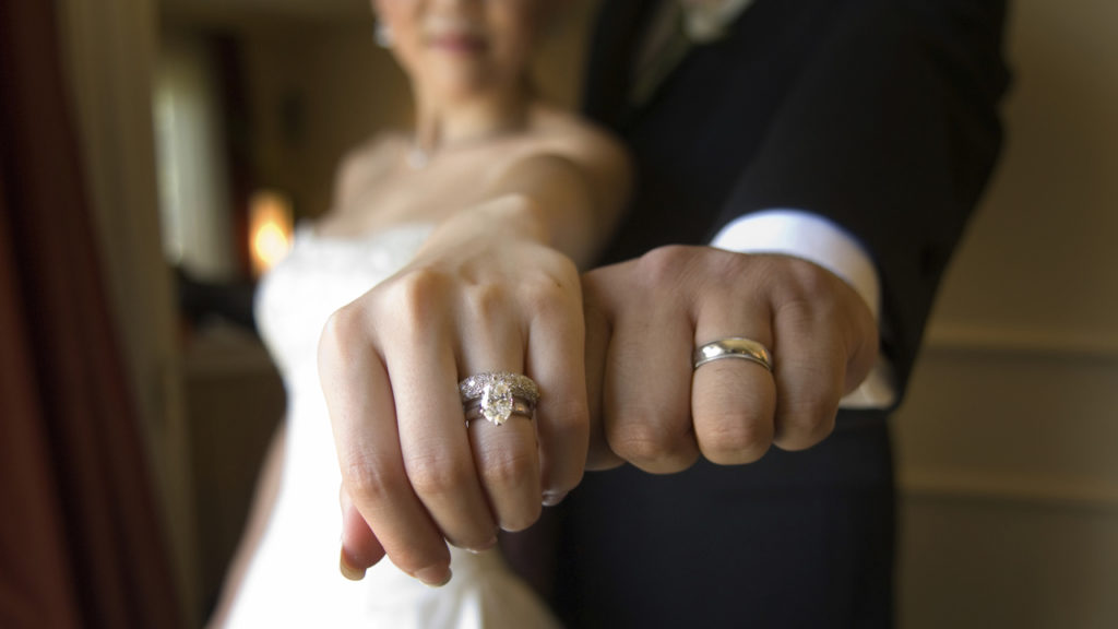 man and woman showing off wedding rings