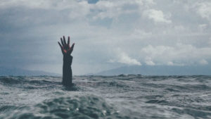Person's arm reaching out of the sea